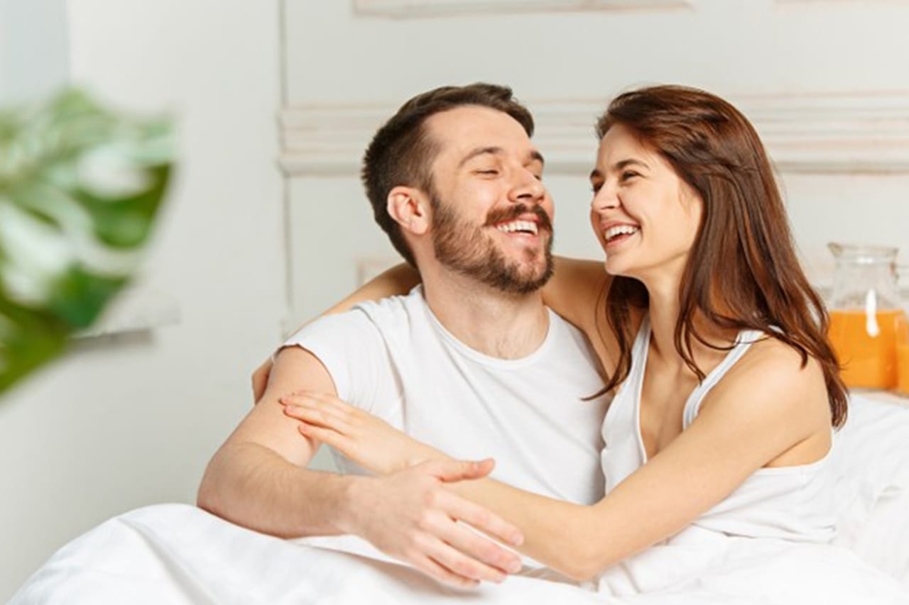 Happy couple laughing together in bed